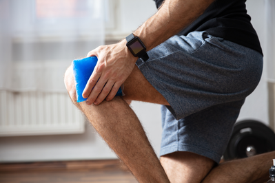 a man holding an ice pack on his knee to relieve pain