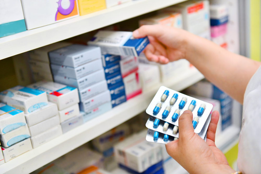 pharmacist grabbing medications from shelf