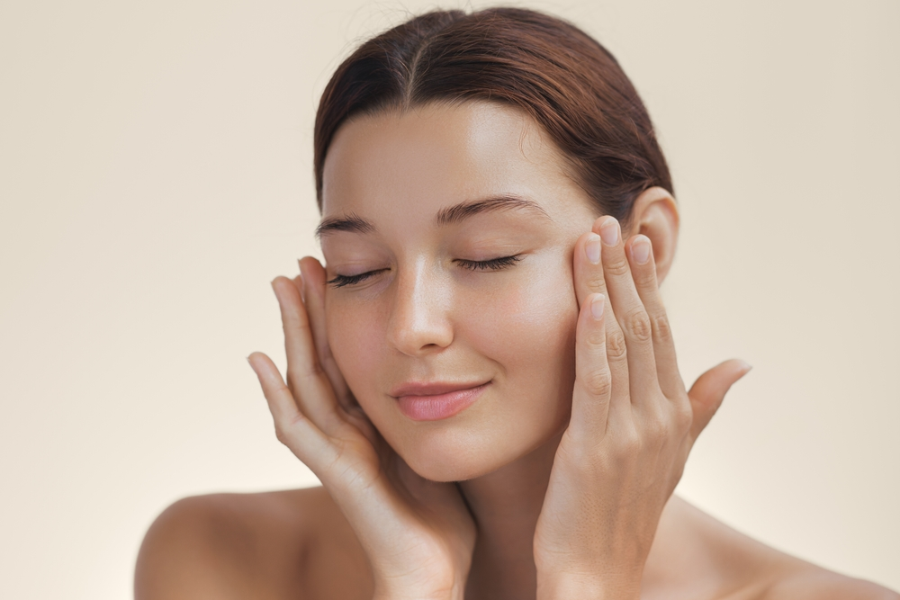 woman applying skincare products to glowing skin